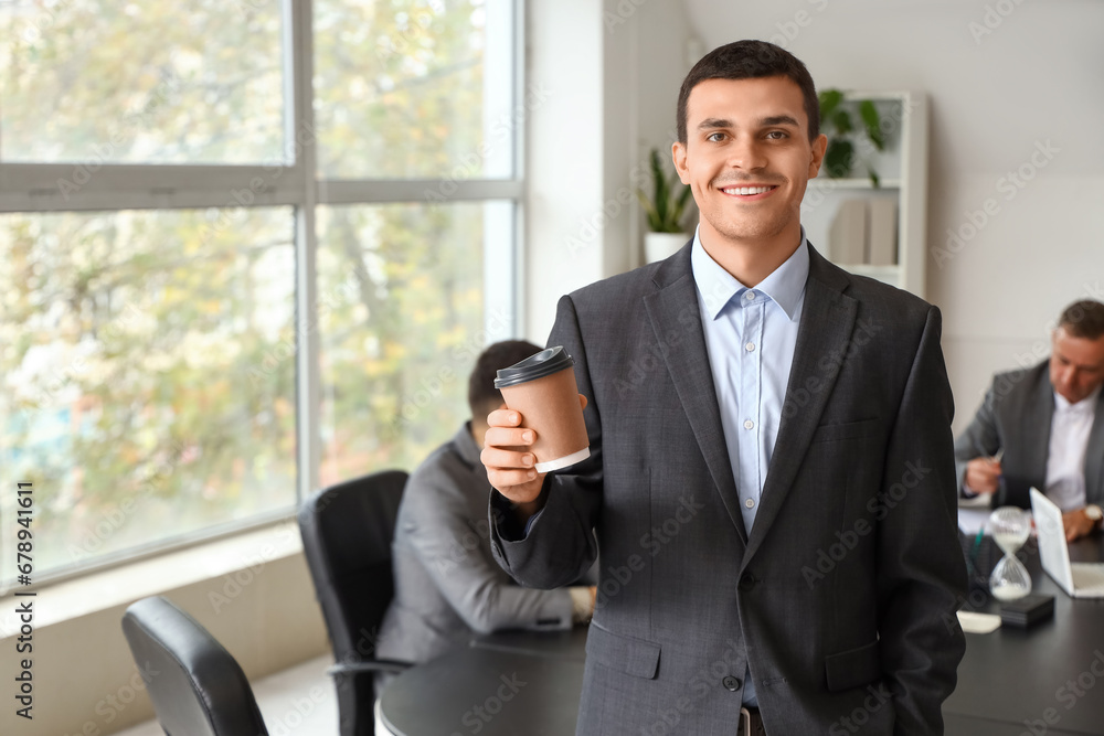 Young businessman with coffee cup in office Young businessman with coffee cup in office