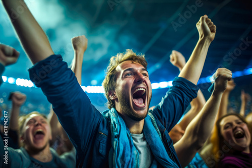 Enthusiastic male sports fan is fully immersed in the excitement of a soccer match with a high-energy crowd in background, her impassioned cheering shows the joy of sport © MVProductions