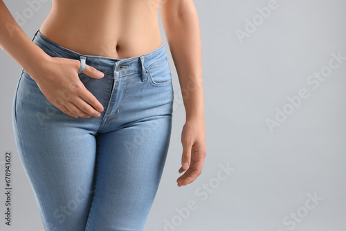 Woman wearing stylish jeans on light gray background, closeup. Space for text © New Africa