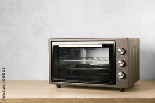 One electric oven on wooden table near light blue wall, space for text
