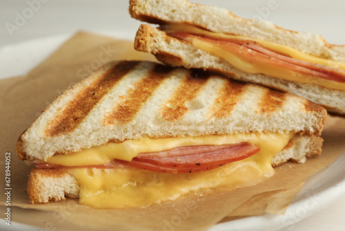 Tasty sandwiches with ham and melted cheese on plate, closeup