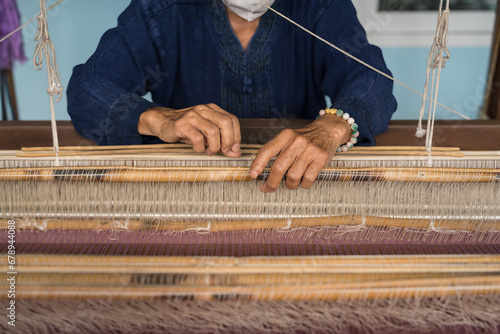 Foto Artisan hands weaving Thai silk on a traditional loom