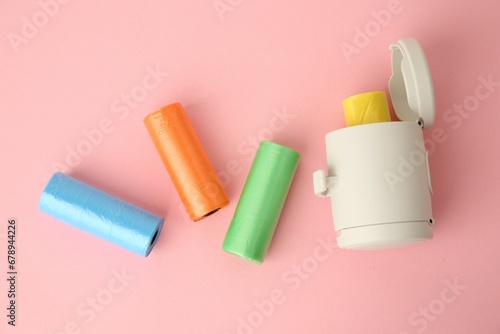 Dog waste bags and dispenser on pink background, flat lay