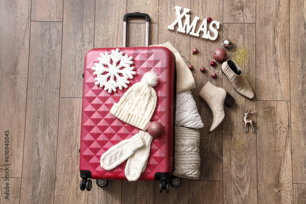 Composition with stylish suitcase, warm clothes and Christmas decorations on wooden floor Composition with stylish suitcase, warm clothes and Christmas decorations on wooden floor