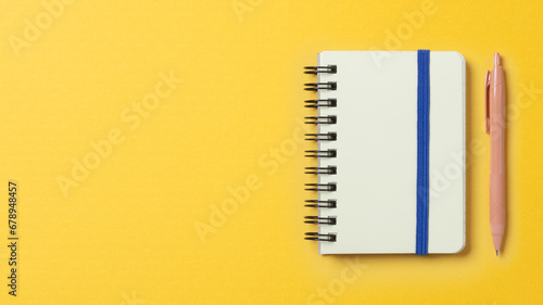 黄色い空間に置かれたノートとペン photo