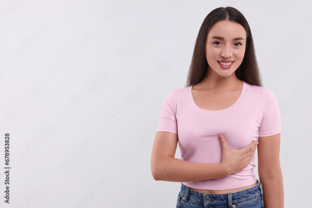 Beautiful happy woman doing breast self-examination on white background, space for text Beautiful happy woman doing breast self-examination on white background, space for text