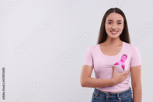 Beautiful young woman with pink ribbon on white background, space for text. Breast cancer awareness © New Africa