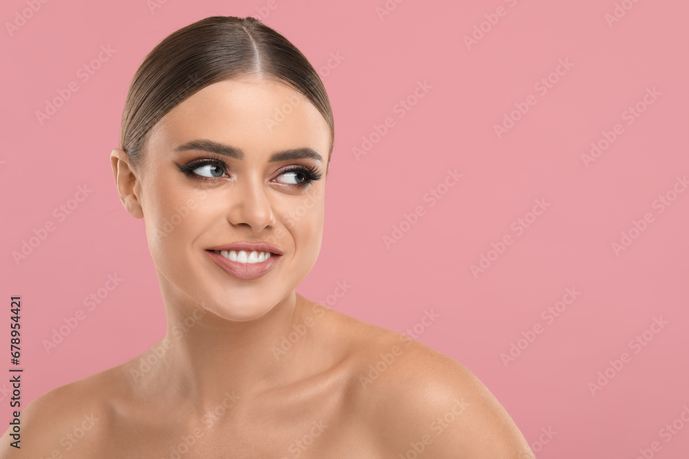 Happy woman with makeup on pink background, space for text