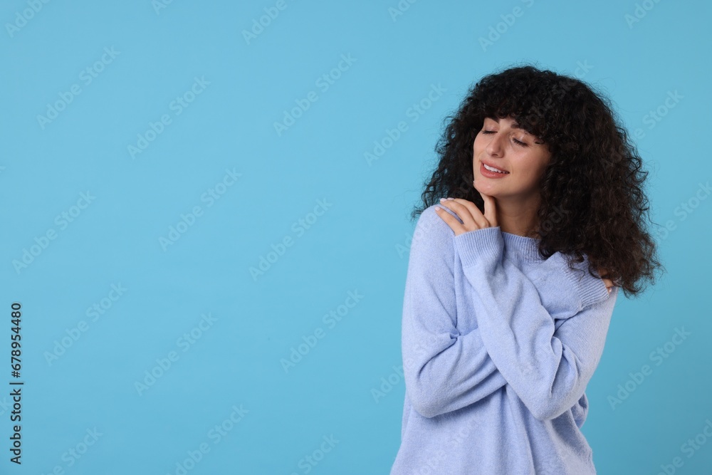 Happy young woman in stylish warm sweater on light blue background, space for text Happy young woman in stylish warm sweater on light blue background, space for text