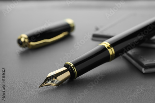Stylish black fountain pen on grey textured table, closeup