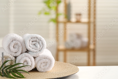 Spa composition. Towels and palm leaves on white table in bathroom  space for text