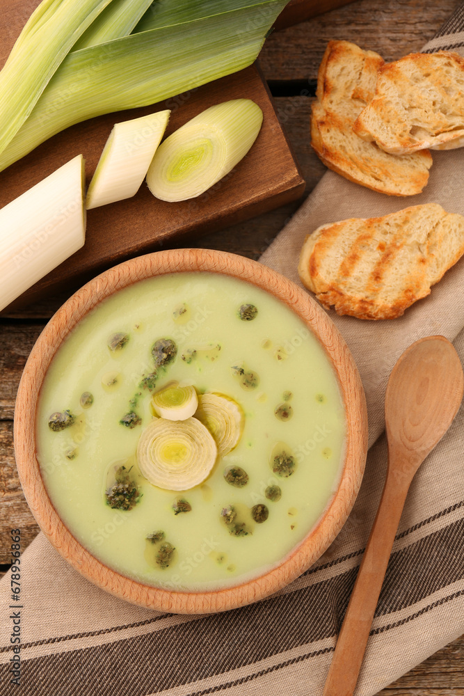Delicious leek soup on wooden table, flat lay Delicious leek soup on wooden table, flat lay