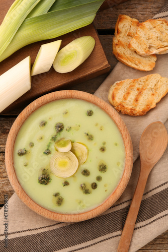 Delicious leek soup on wooden table, flat lay