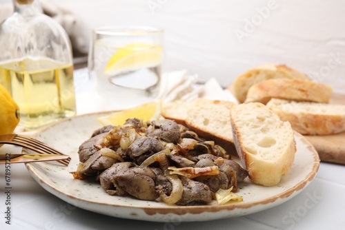 Tasty fried chicken liver with onion served on white tiled table