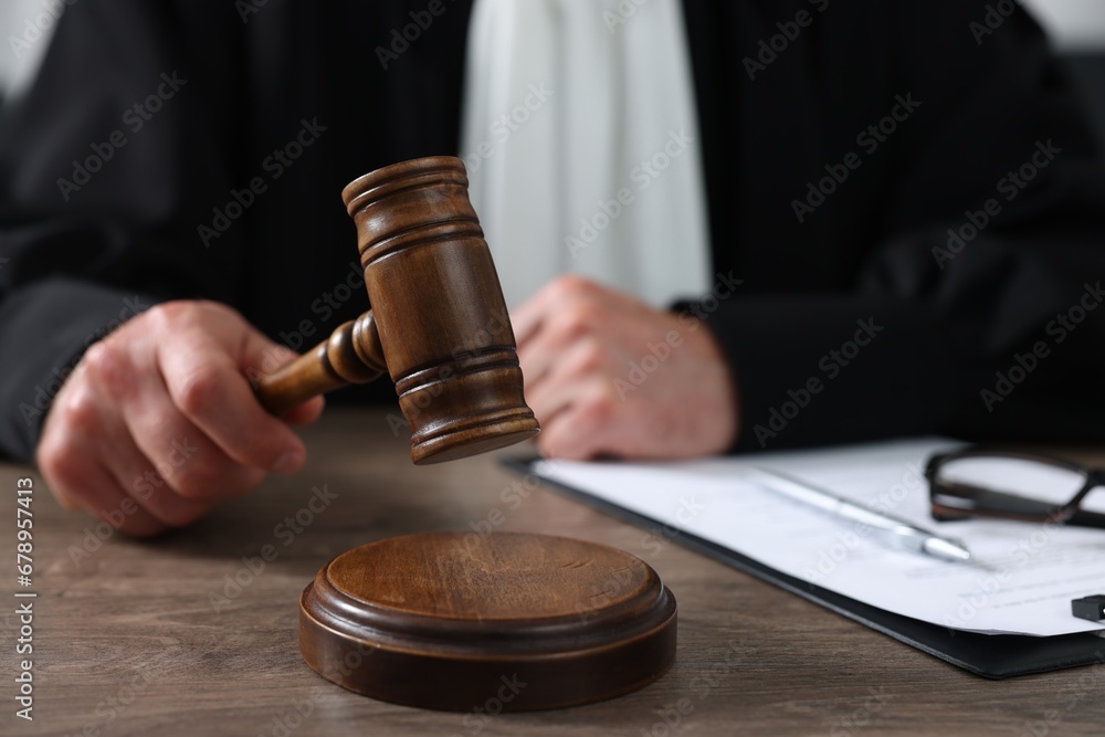 Judge with gavel and papers sitting at wooden table, closeup Judge with gavel and papers sitting at wooden table, closeup