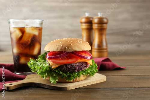 Tasty vegetarian burger with beet patty served on wooden table. Space for text