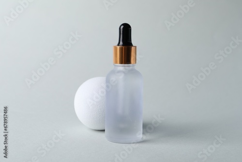 Bottle with cosmetic serum on light grey background