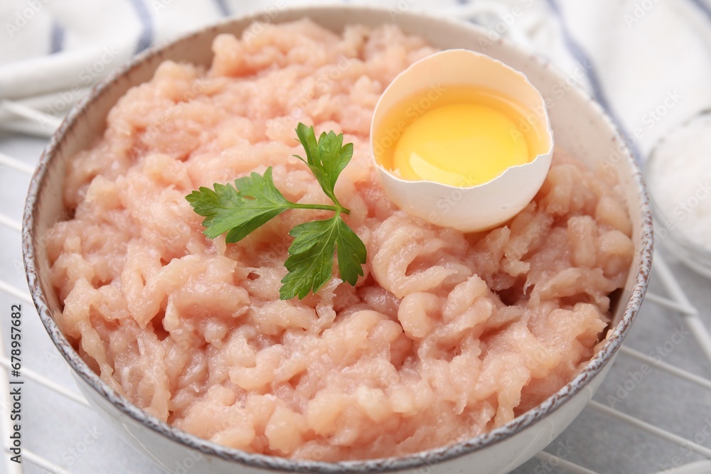 Fresh raw minced meat, parsley and egg in bowl on light grey table, closeup Fresh raw minced meat, parsley and egg in bowl on light grey table, closeup