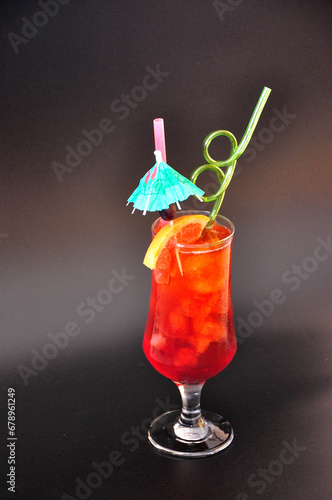 Sex on the beach, a refreshing cocktail in a tall glass with ice and pieces of fruit on a black background.