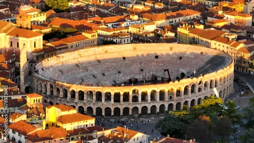 Verona Arena. 
Aerial Drone footage of Verona Arena, flying over Piazza Bra at Golden hour, close to Sunset time, 
With people walk in the square and on top of the arena rooftop. photo