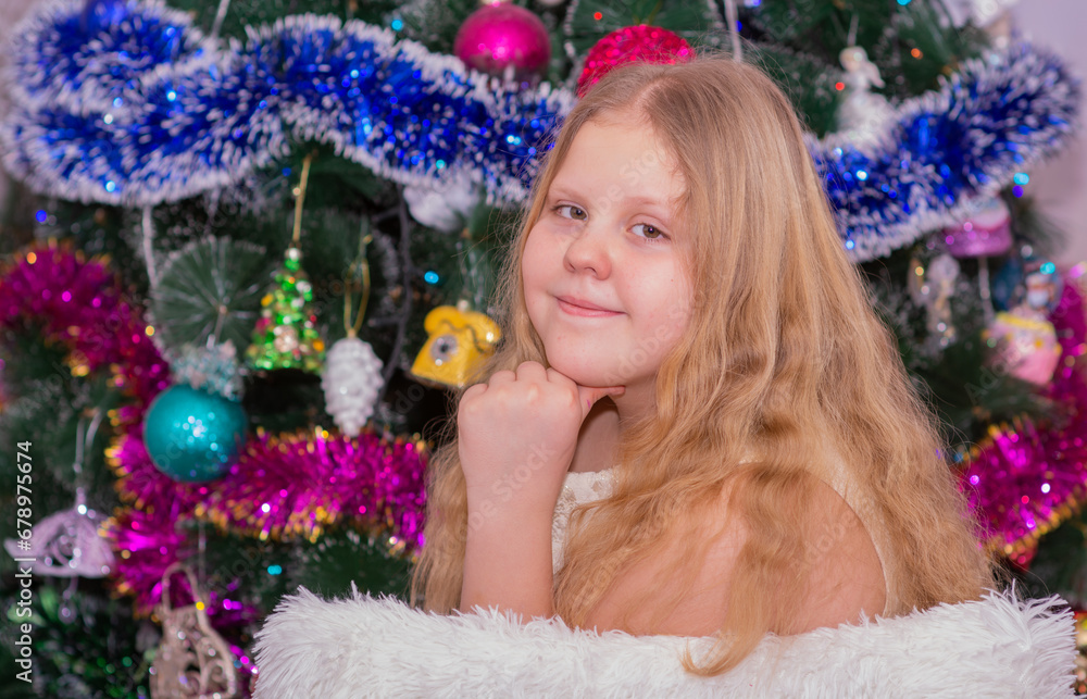 A beautiful elegant girl near the Christmas tree in the New Year. Holiday. New Year. The child is a model.