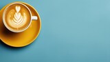 Yellow cup of Cappuccino with latte art on simple blue pastel background, top view