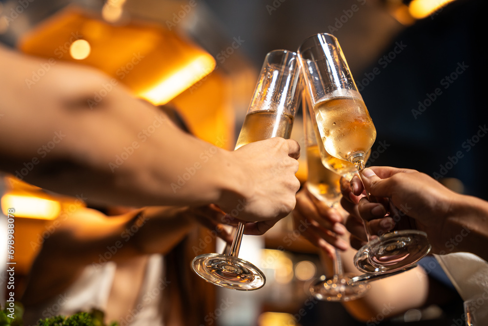 Close-up Group of People Hands Holding Champagne Glass and Cheer Together in Restaurant. They Enjoying with Night Party Together. Party, Lifestyle, Happiness, Cheerful and Celebration Concept. 