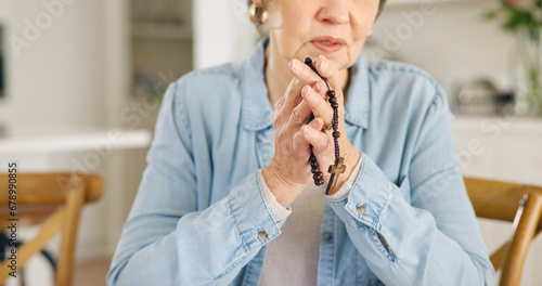 Closeup, old woman or rosary for prayer, faith or religion with guidance, spiritual or peace in a lounge. Apartment, pensioner or elderly person with beads, Christian or worship with Catholic or home photo
