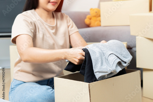 Close-up of happy woman packing donation box with clothes for people in need.