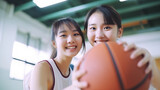 Portrait of cheerful asian girls standing at basketball court turn around looking at camera and holding ball outside