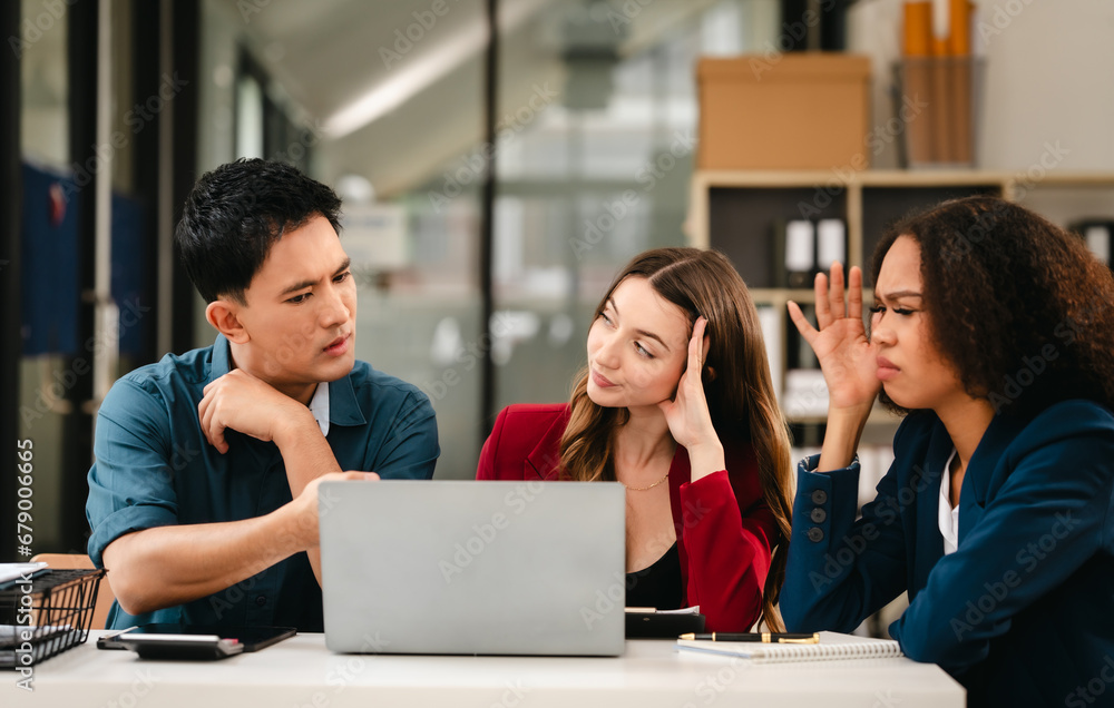 Business team meeting with stressed man rubbing his forehead, while two women review documents, appearing serious and focused. Business team meeting with stressed man rubbing his forehead, while two women review documents, appearing serious and focused.