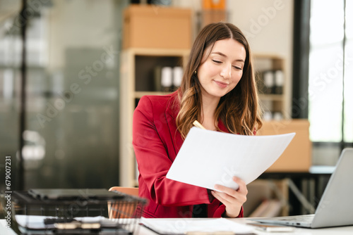 Photos Caucasian businesswoman, likely an accountant or CPA, smiling and holding a coffee cup while working on her laptop