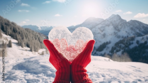 A person holding a heart shaped snow on mountains. © MdBaki