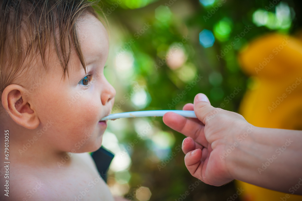 Baby boy eating porridge food, with a spoon. Hungry baby with open mouth enjoying food. Mother feeding her baby Baby boy eating porridge food, with a spoon. Hungry baby with open mouth enjoying food. Mother feeding her baby