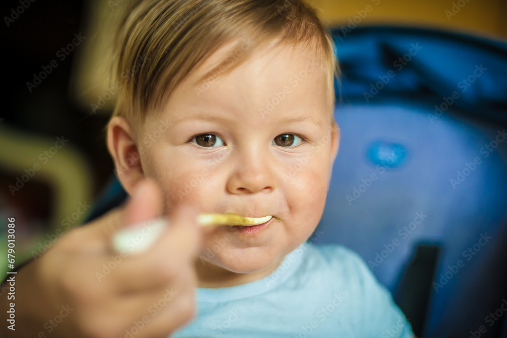 Baby boy eating porridge food, with a spoon. Hungry baby with open mouth enjoying food. Mother feeding her baby Baby boy eating porridge food, with a spoon. Hungry baby with open mouth enjoying food. Mother feeding her baby
