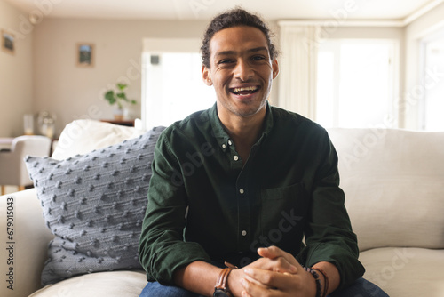 Photos Happy biracial man with long curly hair having video call and laughing in sunny