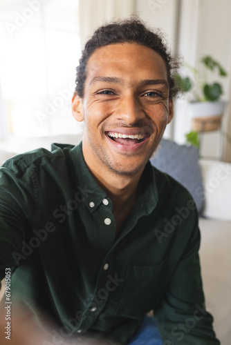 Happy biracial man with long curly hair having video call and laughing in sunny living room at home © WavebreakMediaMicro
