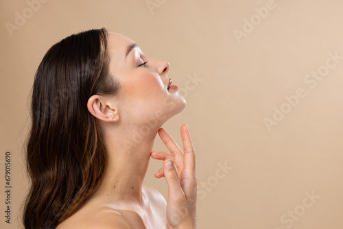 Caucasian woman with brown hair wearing natural makeup on beige background, copy space