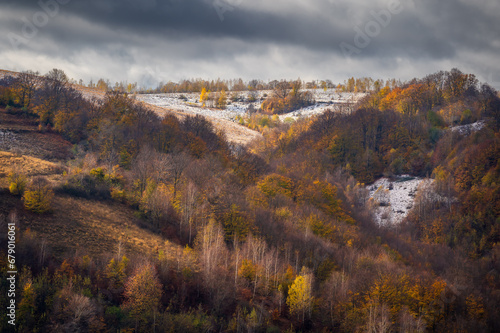Autumn landscape with hills covered by snow in the morning.