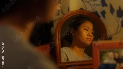 Mirror View of Asian Indonesian Girl Sighing, Sad, and Turned off the Light photo