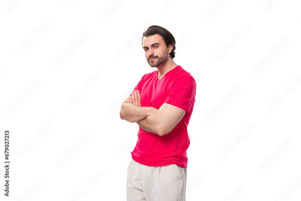 a young european man dressed in a red corporate t-shirt stands with his arms crossed in front of him a young european man dressed in a red corporate t-shirt stands with his arms crossed in front of him
