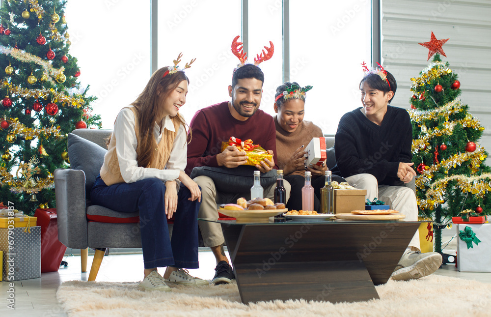 Millennial Asian Indian multinational cheerful male female friends celebrate Christmas Eve and Happy New Year holding showing presents gifts boxes in living room full decoration with Xmas tree