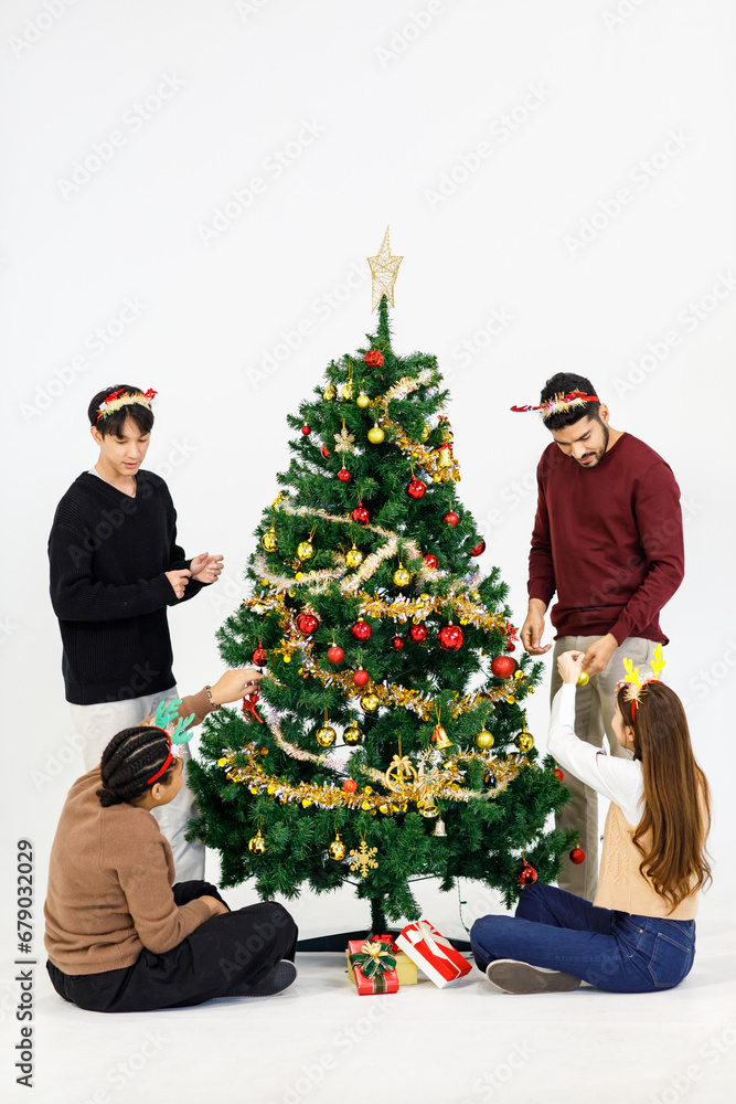 Group of Asian Indian male female friends wearing reindeer antlers headband smiling helping decorating Xmas tree with decoration hanging stuffs celebrating Christmas Eve New Year on white background Group of Asian Indian male female friends wearing reindeer antlers headband smiling helping decorating Xmas tree with decoration hanging stuffs celebrating Christmas Eve New Year on white background