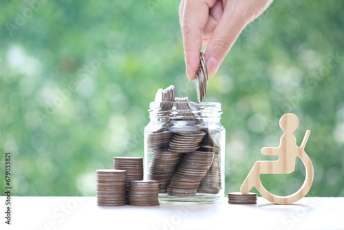 Man on wheelchair and coin money in the glass bottle on natural green background,Save money for prepare in future and handicapped person concept