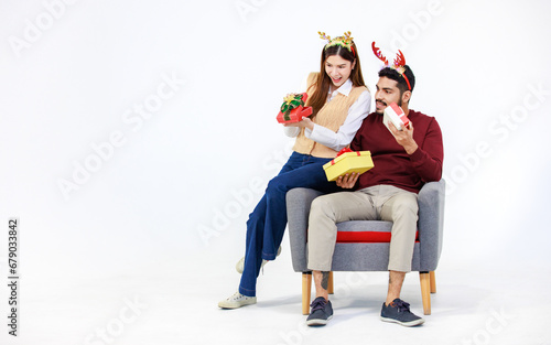 Isolated cutout studio full body shot Asian Indian male female lover couple wear reindeer antlers headband holding exchanging wrapped present gift boxes celebrating Christmas Eve on white background photo