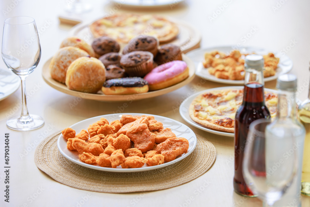 Top view closeup shot of delicious tasty yummy fast foods donuts cupcake pizza and fried chicken on wooden tray and white dish placed on table for group party celebrating Christmas eve and New Year Top view closeup shot of delicious tasty yummy fast foods donuts cupcake pizza and fried chicken on wooden tray and white dish placed on table for group party celebrating Christmas eve and New Year