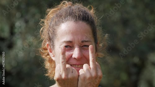 Beautiful woman doing a funny dance before to show with her hands the fuck you expression. Close up