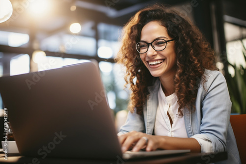 woman boss with joyful expression working on laptop in her office