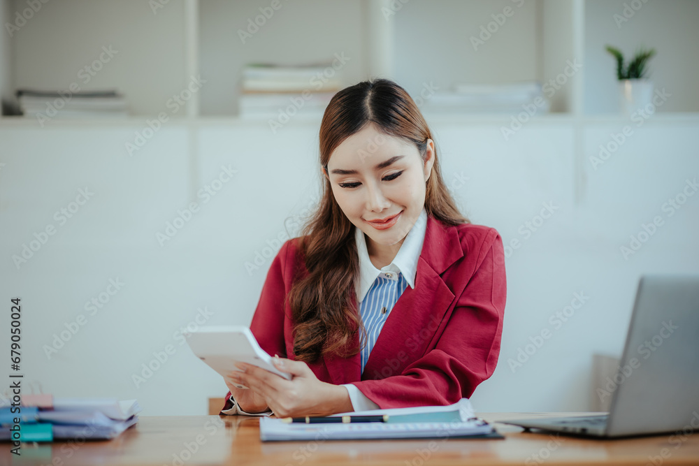 Portrait of a happy beautiful Asian businesswoman.
Working with a tablet in a company office