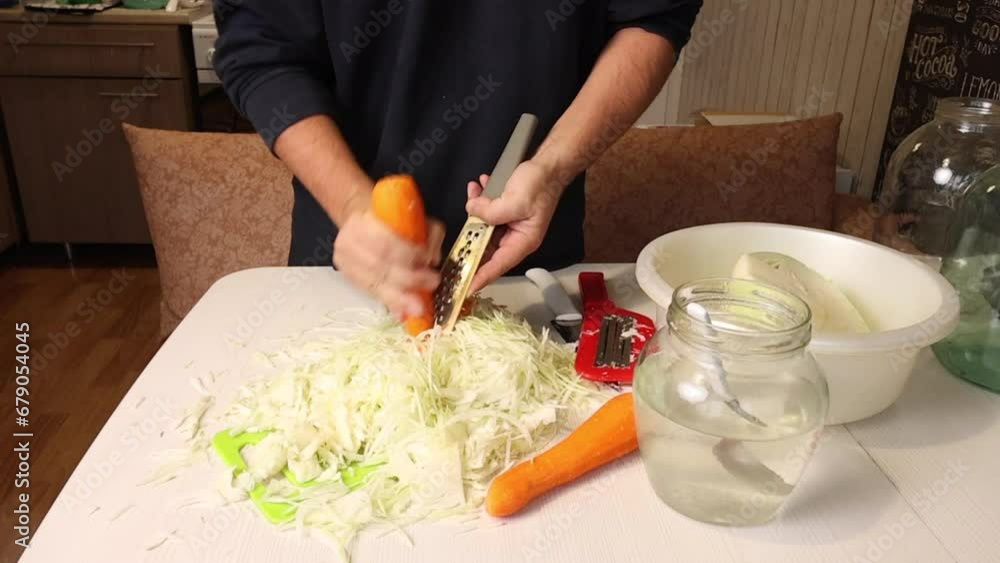 A man cooks sauerkraut at home. Grinds carrots. Overall plan A man cooks sauerkraut at home. Grinds carrots. Overall plan